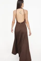 Vestido largo azul marino, de corte fluido, con escote halter, detalles trenzados en los hombros, bolsillos laterales y tajo profundo en la pierna.