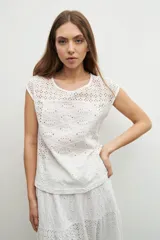 Blusa blanca con bordado calado, de corte recto y mangas cortas.