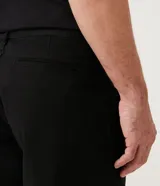 Bermuda de sarga color amarillo, de corte recto, con cierre de botón y cremallera, bolsillos delanteros y traseros.