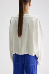 Remera oversize de manga larga y largo cropped color blanco, confeccionada en jersey de algodón, con cuello redondo y terminaciones desgastadas.