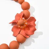 Collar de cuentas redondas color fucsia con dije de flor fucsia y detalles de strass.