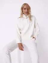 Sweater blanco de tejido de punto, con cuello alto con cierre metálico y mangas largas.