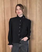 Camisa de manga larga con estampado de cuadros en tonos marrones y azules. Presenta cuello alto con volados, cierre frontal con botones y puños con volados.