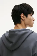 Campera con capucha de felpa color gris oscuro, con cierre frontal, cordón ajustable en la capucha, bolsillos laterales y puños y bajo acanalados. Corte estándar.