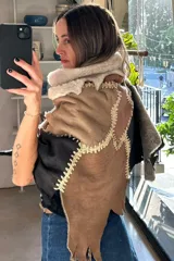Ruana artesanal confeccionada con piezas de napalán unidas mediante técnica de crochet, con diseño de parches en tonos tierra y texturas de piel sintética.