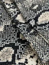 Pantalón tiro alto de pierna ancha con estampado animal print de serpiente en tonos beige, blanco y negro.