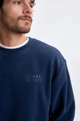 Buzo de polar azul marino con cuello redondo, mangas largas y puños elásticos. Presenta el logo de la marca bordado en el pecho.
