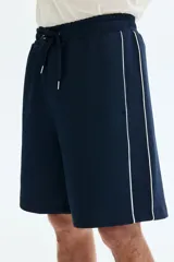 Short azul marino de punto con leve brillo, cintura elástica con cordón de ajuste y ribetes laterales en color blanco.