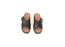 Sandalia de cuero negro con textura de reptil, diseño de tiras cruzadas con ajuste de velcro y suela de poliuretano con plataforma.