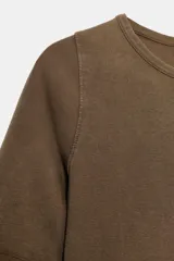 Camiseta de algodón color terracota con efecto lavado, cuello redondo y manga corta. Posee un bajo redondeado.