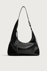 Bolso de hombro asimétrico color negro con acabado liso. Cuenta con un compartimento principal con cierre de cremallera y un bolsillo frontal con cremallera. Incluye asa de hombro ajustable.