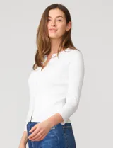Cardigan blanco de tejido liviano con trama en relieve, cuello a la base y cierre frontal con botones a tono. Presenta mangas tres cuartos.