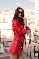 Chaqueta de cuero ovino color rojo, con cierre frontal de metal, cuello redondo y mangas largas con puños anchos ajustables mediante broches metálicos.