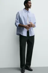 Pantalón de corte regular fit confeccionado en tejido mezcla de algodón. Presenta cintura con detalle de pliegues en el delantero, bolsillos frontales y bolsillos traseros de vivo con botón. Cierre frontal con cremallera y botón.