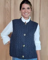 Chaleco de punto con diseño de trenzas, color gris oscuro, con cierre frontal de botones grandes y bolsillos laterales.