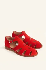 Sandalias de gamuza color marrón, estilo romano con diseño en T, tiras con aberturas laterales y cierre de hebilla metálica en el tobillo. Cuenta con tacón bajo de madera.