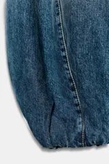 Jeans de tiro medio confeccionados en denim azul con efecto deslavado, corte holgado con diseño de volumen abullonado en las piernas y bajo con puño elástico. Cuentan con trabillas, bolsillos delanteros y traseros, y costuras decorativas marcadas.