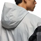 Campera rompevientos con capucha Nike Jordan, diseño color block en tonos gris claro, gris oscuro y negro. Presenta cierre frontal completo, bolsillos laterales y logo Jumpman bordado en el pecho.
