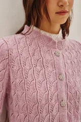 Cardigan de punto calado en color rosado, con cuello redondo y cierre frontal de botones decorativos con pedrería brillante.
