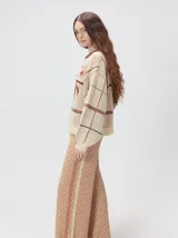 Sweater de punto con diseño geométrico y gráfico frontal en color rojo. Presenta cuello redondo, mangas largas holgadas y un ajuste suelto.