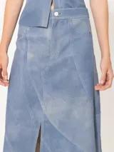 Falda midi de cuero ovino celeste con recortes diagonales y tajo frontal.