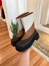 Botas de cuero color marrón y beige con caña media, cierre lateral y suela track.