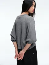 Sweater de tejido de punto color gris, con silueta relajada, mangas estilo murciélago y cuello a la base.