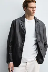 Blazer de corte relajado confeccionado en piel genuina, con cuello de solapas de muesca, manga larga y cierre frontal de tres botones. Presenta bolsillos de vivo en la cadera y un bolsillo interior.