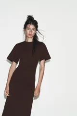 Vestido largo color marrón oscuro, con cuello redondo, manga corta y detalle de drapeado fruncido en el lateral izquierdo, terminando en línea evasé.