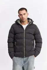 Campera puffer con capucha, diseño acolchado, cierre frontal y bolsillos laterales. Presenta un interior en contraste de color verde oliva.