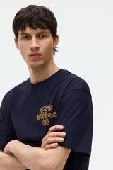 Remera boxy de algodón color negro, con cuello redondo acanalado, mangas cortas y hombros caídos. Presenta un pequeño estampado amarillo en el pecho con el texto "sports archives 08".