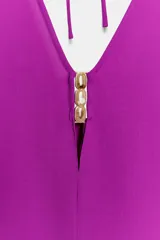 Mono corto de color fucsia, con escote en pico delantero y en la espalda, mangas anchas y largas, y detalle de fornitura dorada en el escote delantero con tiras finas para atar en la espalda.