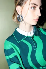 Caravanas grandes con forma de círculo irregular, con textura y diseño de puntos blancos sobre fondo negro y azul, y un centro dorado.