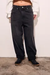 Jean de corte baggy con diseño barrel, tiro medio y acabado en color negro lavado. Presenta cierre frontal con botón y bolsillos laterales y traseros.