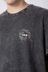 Remera de algodón con efecto de lavado desgastado tipo snow wash, de corte semi-oversize, cuello redondo y manga corta. Presenta un pequeño estampado gráfico circular en el pecho.