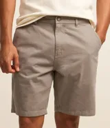Bermuda masculina de corte recto confeccionada en sarga de algodón. Presenta cierre frontal con botón y cremallera, bolsillos laterales y traseros, y diseño liso sin estampados.