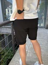 Bermuda negra de gabardina con lycra, corte a la rodilla y ruedo doblado.