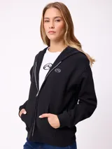 Canguro con cierre frontal de la marca Rusty, en color beige. Presenta capucha, bolsillos tipo canguro y logo bordado en el pecho.