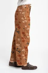 Jean de corte baggy y tiro medio, confeccionado en algodón peinado. Presenta un diseño estampado con motivos florales en tonos tierra sobre una base color marrón.