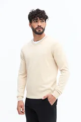 Sweater de punto color gris melange, con escote en V, manga larga y logo bordado en el pecho. Presenta puños y ruedo acanalados.