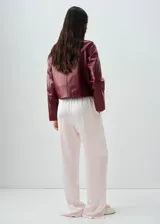 Chaqueta de cuero de corte recto con cuello camisero, cierre frontal de botones y dos bolsillos de parche con solapa en la parte delantera.