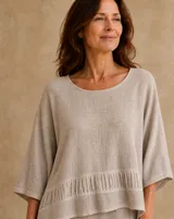 Blusa de lino color beige, de corte amplio y holgado, con escote redondo, mangas tres cuartos anchas y detalle de fruncido horizontal en la parte inferior.