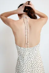 Vestido largo de color negro con cuello halter y escote recto. Presenta un diseño fluido con cierre de cremallera oculta en la espalda y lazada ajustable en el cuello.