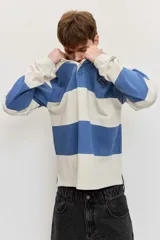 Chomba de friza de manga larga con diseño de rayas horizontales anchas en color beige y azul, cuello polo y pequeño bordado en el pecho.
