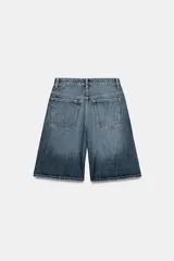 Bermuda baggy de denim azul con tiro medio, trabillas para cinturón y diseño de cinco bolsillos. Presenta cierre frontal con cremallera y botón metálico.