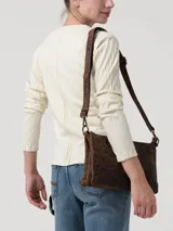 Remera de manga larga en color blanco hueso, con cuello redondo y cierre frontal parcial con botones. Presenta un diseño de tejido trenzado con textura en las mangas y cuerpo liso.