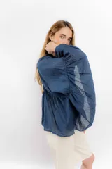 Camisa de algodón con diseño romántico, mangas amplias y detalles de puntillas verticales en el frente. Presenta un corte holgado y fluido.