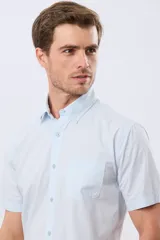 Camisa de manga corta de algodón en color celeste con microdiseño geométrico a cuadros, cuello camisero y bolsillo frontal con logo bordado.