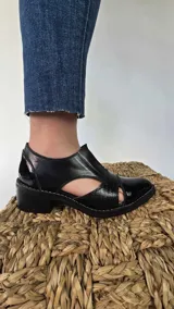 Zapatos de cuero negro con aberturas laterales, taco medio y detalles de textura en la puntera.