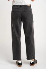 Jean de corte baggy con tiro medio, confeccionado en denim de color gris lavado. Presenta un diseño de pierna ancha con costuras horizontales a la altura de la rodilla y cierre frontal con botón y cremallera.
